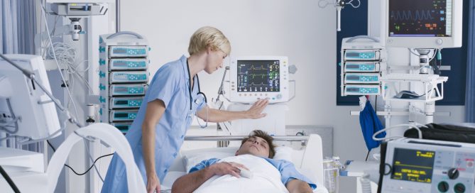 Nurse in ICU with patient hooked up to various electronic monitoring systems that require continuous power.
